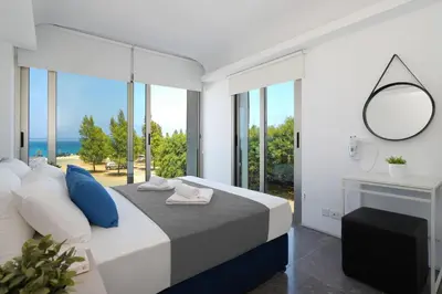 a bedroom with a bed with a view of the ocean at Jenny - Beachfront Apartment in Protaras