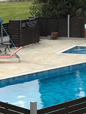 a swimming pool with a table and a chair next to it at A+A Apartment in Kiti