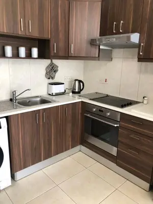 a kitchen with wooden cabinets and a sink and a stove at A+A Apartment in Kiti