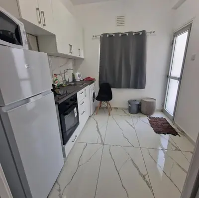 a kitchen with white marble floors and a refrigerator at Cozy 1 bedroom apartment Larnaca city-center F in Larnaka