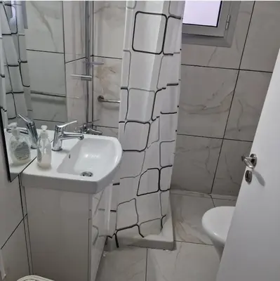 a white bathroom with a sink and a shower at Cozy 1 bedroom apartment Larnaca city-center F in Larnaka