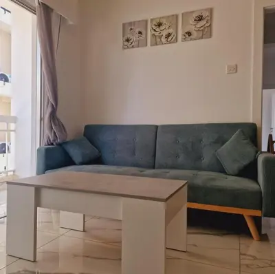 a living room with a blue couch and a table at Cozy 1 bedroom apartment Larnaca city-center F in Larnaka