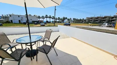 a table with chairs and an umbrella on a patio at Beach Love BeachFront Apartment in Pyla