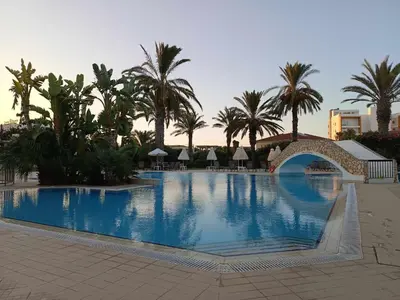 a large swimming pool with a bridge and palm trees at Pernera Nest in Protaras