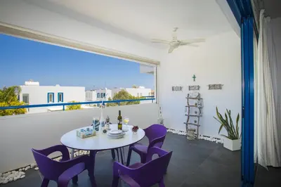 a dining room with a table and purple chairs at Protaras Aster Seaside Suite in Protaras