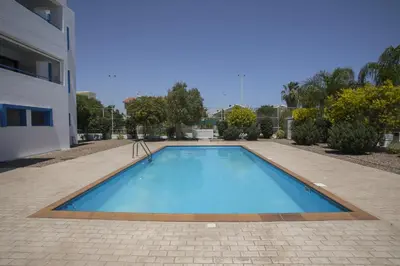 a large blue swimming pool next to a building at Protaras Aster Seaside Suite in Protaras