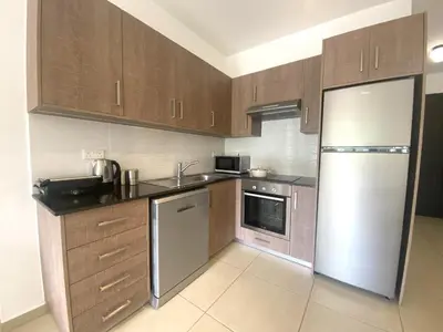 a kitchen with wooden cabinets and a stainless steel refrigerator at DPSAE09 Mythical Sands Resort - Two Bedroom Apt with pool in Paralimni