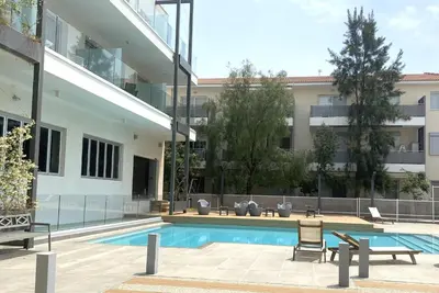 a building with a swimming pool and two chairs next to a building at DPSAE09 Mythical Sands Resort - Two Bedroom Apt with pool in Paralimni