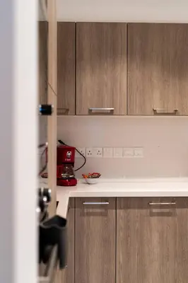 a kitchen with wooden cabinets and a white counter top at Hubstay - Seaview Villa Oriana in Larnaca in Larnaka