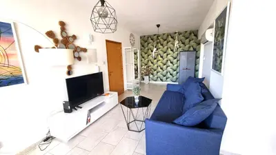 a living room with a blue couch and a tv at Beach Haven: 7-Minute walk to the beach + Pool in Larnaka