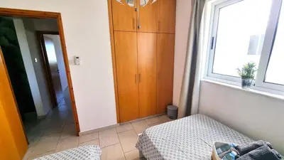 a room with a cabinet and a bed and a window at Beach Haven: 7-Minute walk to the beach + Pool in Larnaka