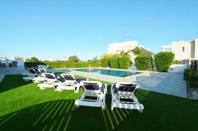 a row of lounge chairs and a swimming pool at Villa Aquamarine in Ayia Napa