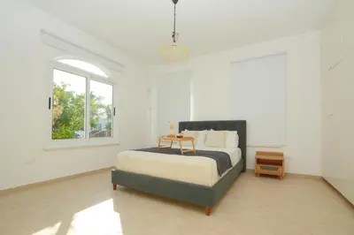 a white bedroom with a bed and a window at Villa Aquamarine in Ayia Napa