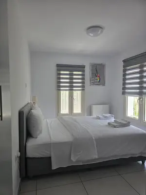 a bedroom with a large bed with two windows at Maryland River Liz in Kakopetria