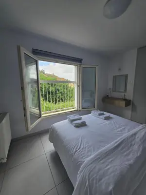 a bedroom with a white bed and a large window at Maryland River Liz in Kakopetria