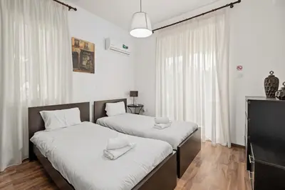 two beds in a room with white walls and wood floors at Villa with private pool in Pervolia, Larnaca in Pervolia