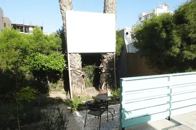 a table and chair in a garden with a sign at Under the Palms in Nicosia