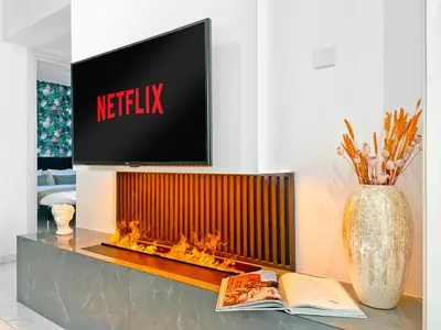 a living room with a tv and a table with a book at The Encino - luxury seaside suite in Larnaka