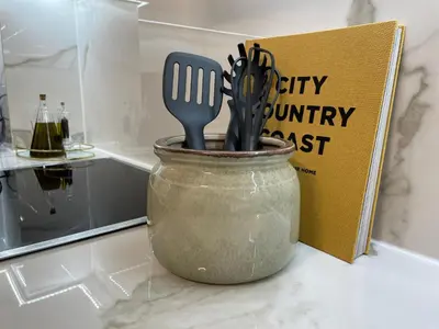 a pot with utensils in it next to a book at The Encino - luxury seaside suite in Larnaka