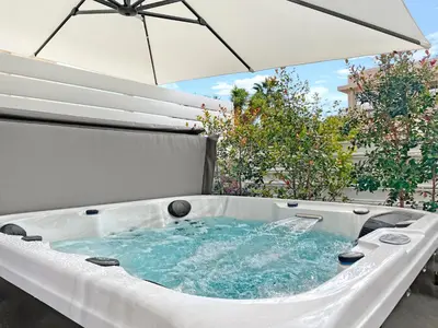 a hot tub with an umbrella on a patio at The Encino - luxury seaside suite in Larnaka