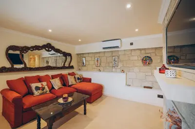 a living room with a red couch and a stone wall at No 1 Mandria in Limassol