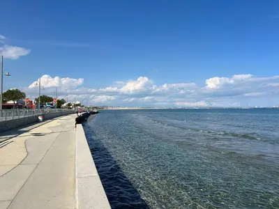 a person sitting on a sidewalk next to the water at Superb Seaview Flat, Prime Area in Larnaka