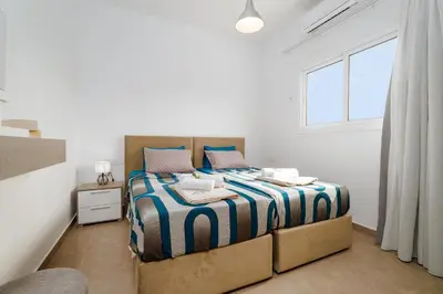 a bedroom with a bed with a blue and white comforter at SunnyVillas 1 Bedroom Central Protaras in Protaras