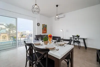 a dining room and living room with a table and chairs at SunnyVillas 1 Bedroom Central Protaras in Protaras