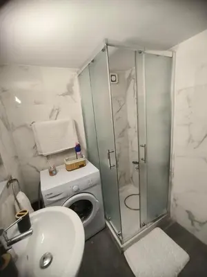 a bathroom with a shower and a sink and a washing machine at Sunorama Beach Garden - Seaview in Larnaka