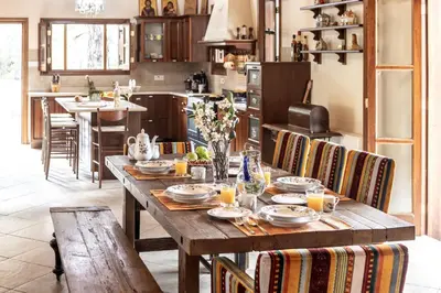 a kitchen with a wooden table with chairs and a tableasteryasteryasteryasteryastery at Troodos Mature Pine Chalet in Pedoulas