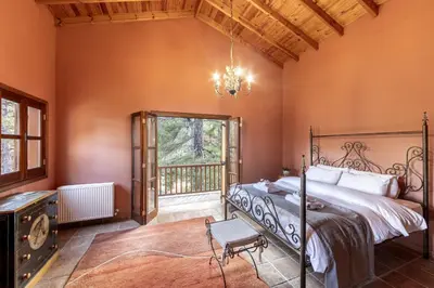 a bedroom with a bed and a balcony at Troodos Mature Pine Chalet in Pedoulas