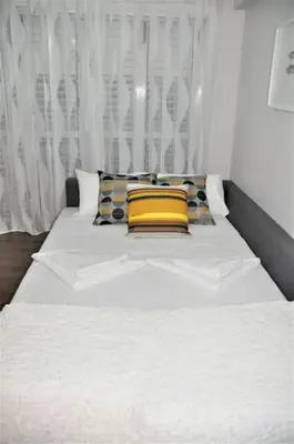 a white bed with yellow pillows in a bedroom at Liliana Sea View Suite in Larnaka