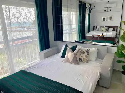 a bedroom with a white bed with pillows and a mirror at Aria Sea View Studio in Larnaka