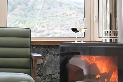 a glass of wine sitting next to a fireplace at Oikou Thea Guesthouse in Oikos