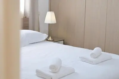 a white bed with two towels on top of it at Oikou Thea Guesthouse in Oikos