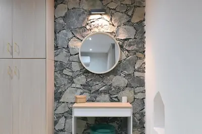 a bathroom with a stone wall and a mirror at Oikou Thea Guesthouse in Oikos