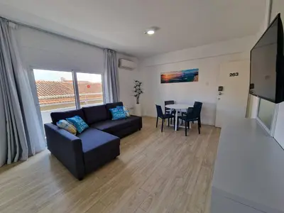 a living room with a couch and a table with chairs at Kitieos Central Apts 100m from Finikoudes Beach in Larnaka