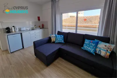 a living room with a couch and a kitchen at Kitieos Central Apts 100m from Finikoudes Beach in Larnaka