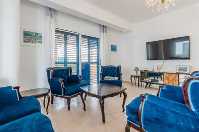 a living room with blue chairs and a tv at Seaview Sanctuary House in Larnaka