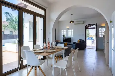 a dining room with a table and white chairs at Lumina 2-Bedroom Villa and Pool in Ayia Napa in Ayia Napa