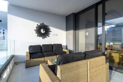 a living room with two couches and a clock on the wall at Beachcomber 2-Bedroom Apartment in Larnaca in Larnaka