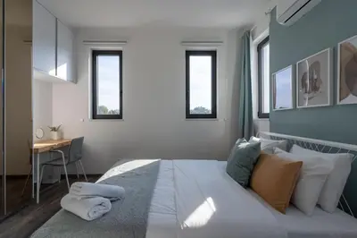 a bedroom with a bed and a desk and windows at Thálassa 2-Bedroom Apartment in Larnaca in Larnaka