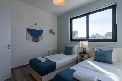 a hotel room with two beds and a window at Thálassa 2-Bedroom Apartment in Larnaca in Larnaka