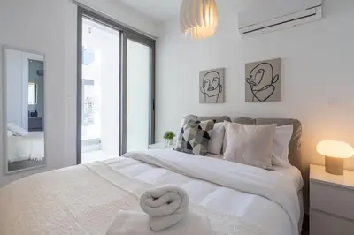 a white bedroom with a large bed and a window at Stars 1-Bedroom Apartment in Larnaca in Larnaka