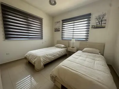 two beds in a bedroom with two windows at Kyklades Resort Excellence in Paralimni