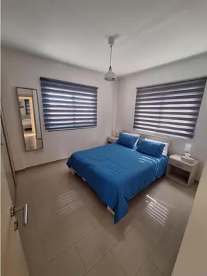 a bedroom with a blue bed and two windows at Kyklades Resort Excellence in Paralimni