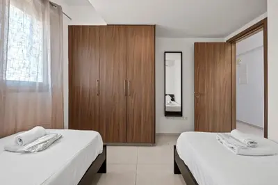 a bedroom with two beds and a wooden cabinet at Downtown 2 Bedroom Penthouse in Larnaka