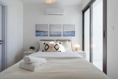 a white bedroom with a large bed with towels on it at Moon Light 1-Bedroom Apartment in Larnaca in Larnaka