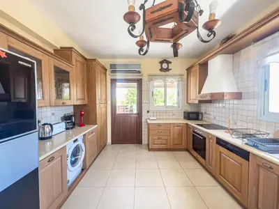 a kitchen with wooden cabinets and a washer and dryer at The Brilliant Villa in Protaras
