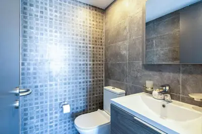 a bathroom with a white toilet and a sink at Maryam's 2-BR Apt Facing Larnaca Harbor With Pool in Larnaka